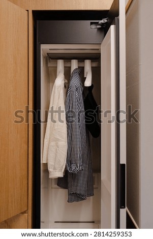 An interior view of a modern steamer or drying cabinet with shirts and clothing items on hangers