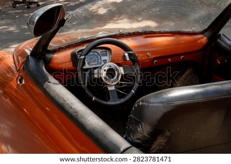 Interior view of modified retro brown cabriolet featuring black sports steering wheel and classic speedometer dial.