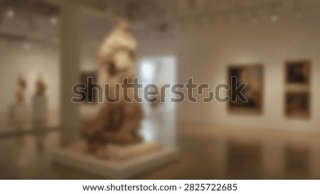 Interior view of a museum gallery showcasing a large classical sculpture and several framed paintings on the walls.