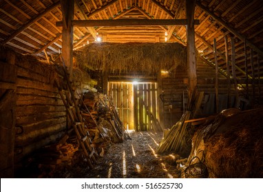 Interior View Of The Old Rural Barn Full Of Hay, Firewood, Tools And Trash