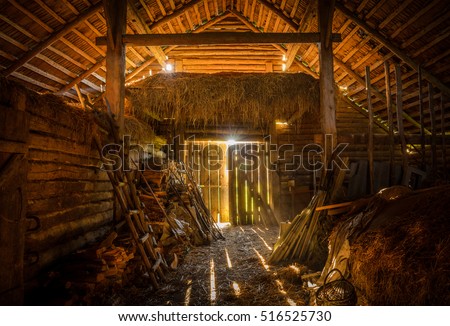 interior view of the old rural barn full of hay, firewood, tools and trash