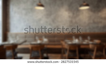 Interior view of a restaurant dining area with wooden tables, chairs, and booth seating, illuminated by warm pendant lights.