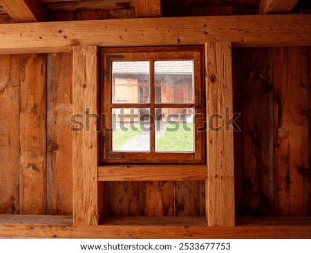 Interior view of a rustic wooden cabin window with an outside view of a yard.