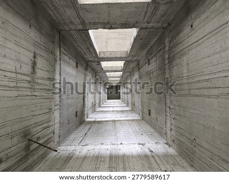 Interior view of an unfinished elevator shaft in a building under construction. Concrete walls, repetitive geometric structure, and strong perspective lines create a tunnel-like effect with natural light entering from the top openings. Industrial architecture background.