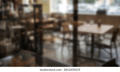 Interior view of a warm and inviting cafe with tables and chairs arranged for customers, seen through a window.