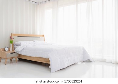 Interior white bedroom with white curtains and white pillows on wooden bed elegant classic for rest and sleep. Modern white bedroom bright.