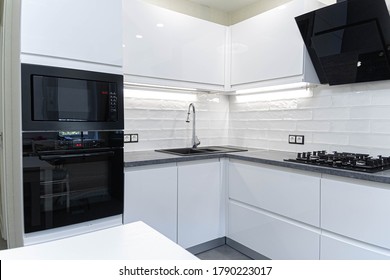 Interior Of White Furniture Of A Compact Kitchen, Glossy Cabinets With Built-in Household Appliances.