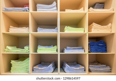 Interior Of White Plastic Cabinet Or Clothing Open Wardrobe With Stacked Piles Of Clean Colorful Linen On Shelves. Furniture Design, Hotel, Hospital Or Kindergarten Concept.