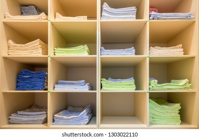 Interior Of White Plastic Cabinet Or Clothing Open Wardrobe With Stacked Piles Of Clean Colorful Linen On Shelves. Furniture Design, Hotel, Hospital Or Kindergarten Concept.