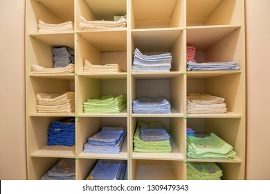 Interior Of White Plastic Cabinet Or Clothing Open Wardrobe With Stacked Piles Of Clean Colorful Linen On Shelves. Furniture Design, Hotel, Hospital Or Kindergarten Concept.