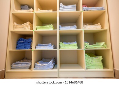 Interior Of White Plastic Cabinet Or Clothing Open Wardrobe With Stacked Piles Of Clean Colorful Linen On Shelves. Furniture Design, Hotel, Hospital Or Kindergarten Concept.