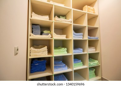 Interior Of White Plastic Cabinet Or Clothing Open Wardrobe With Stacked Piles Of Clean Colorful Linen On Shelves. Furniture Design, Hotel, Hospital Or Kindergarten Concept.