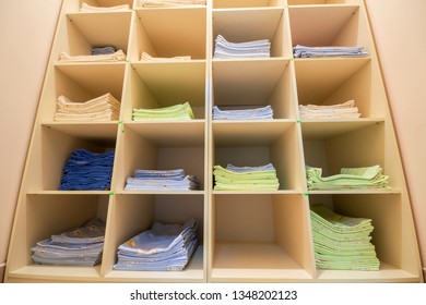 Interior Of White Plastic Cabinet Or Clothing Open Wardrobe With Stacked Piles Of Clean Colorful Linen On Shelves. Furniture Design, Hotel, Hospital Or Kindergarten Concept.