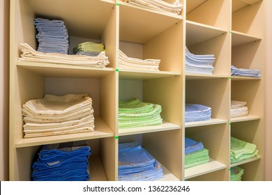 Interior Of White Plastic Cabinet Or Clothing Open Wardrobe With Stacked Piles Of Clean Colorful Linen On Shelves. Furniture Design, Hotel, Hospital Or Kindergarten Concept.