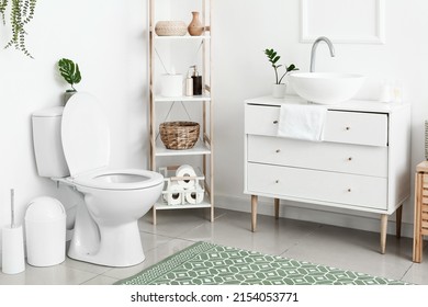 Interior of white restroom with toilet bowl and chest of drawers - Shutterstock ID 2154053771