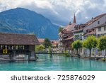 INTERLAKEN, SWITZERLAND - SEPTEMBER 2017:  Bridge over Aare river, with tourists , buildings on the riverside and mountain  in background.