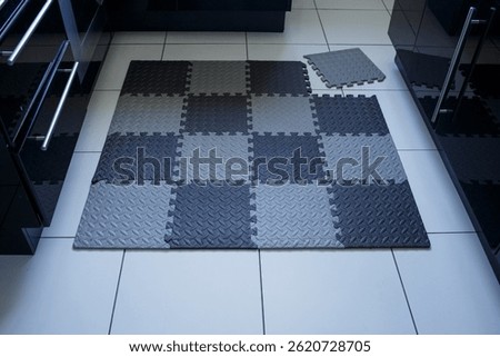 Interlocking foam tiles on kitchen floor with one tile removed, showing modular flooring system for home improvement, flooring suppliers, hardware stores, renovation use.