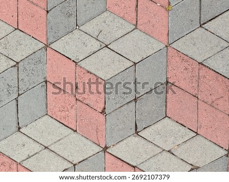 Interlocking rhomboid paving blocks in three colors create a striking three dimensional cube illusion Textured surface of concrete pavers forms a captivating geometric background