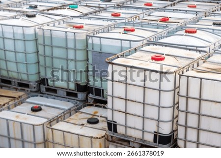 Intermediate bulk containers (IBCs) filled with liquids are neatly arranged in rows on pallets. This industrial storage bulk for material handling chemical storage.