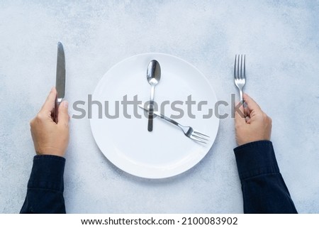 Intermitted farsting diet concept - empty plate and hands with fork and knife