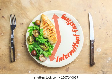 Intermittent fastin concept. One-third plate with healthy food and two-third plate is empty. Chicken fillet, arugula and tomatoes on a plate. Top view. Flat lay - Shutterstock ID 1507140089