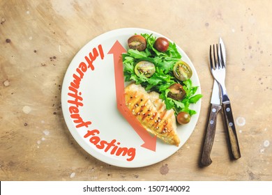 Intermittent fastin concept. One-third plate with healthy food and two-third plate is empty. Chicken fillet, arugula and tomatoes on a plate. Top view. Flat lay - Shutterstock ID 1507140092