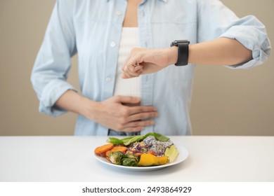 Intermittent fasting concept, Close-up on clock and people feeling hungry waiting time to eat during intermittent fasting diet session