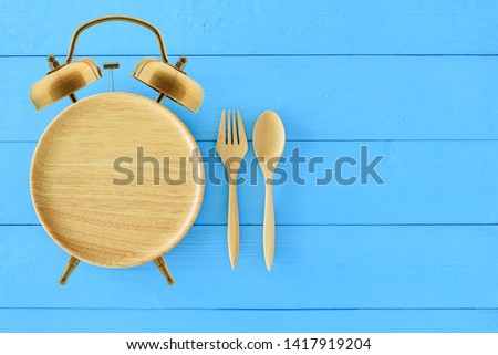 Intermittent fasting, diet and weight loss concept : Clock shaped wood dish, spoon and fork. Eco-friendly plate  kitchen utensil as alarm clock with ringing bell, depict alert or reminder time to eat
