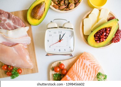  Intermittent fasting and Healthy food. Concept.Alarm clock and Keto diet food ingredients on white table.Ketogenic mean Low carb and High fat. - Shutterstock ID 1398456602