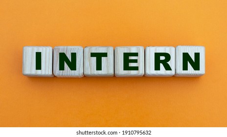 INTERN - word on wooden cubes on a beautiful yellow background. Info concept