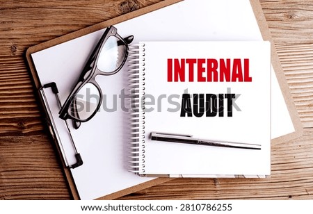 Internal audit concept with notebook clipboard eyeglasses and pen on wooden desk representing corporate compliance. 