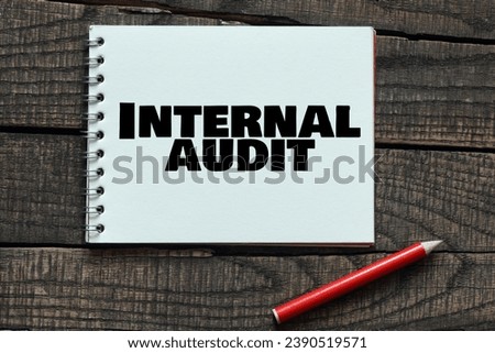 INTERNAL AUDIT words in a notebook on a wooden table.