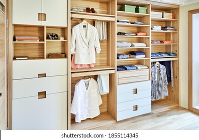 Internal details of the wooden wardrobe with slide out rack for coathangers. Modern wardrobe with clothes hanging on slide out racks and folded on the shelves. Modern furniture