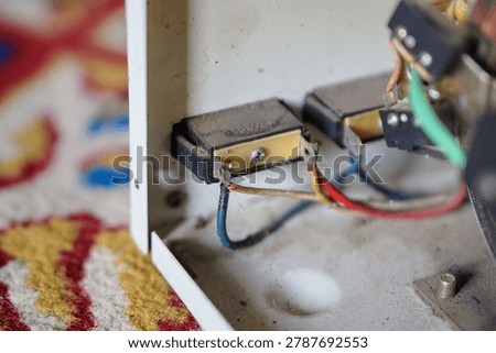 Internal electrical wiring and switch terminals inside a dirty metal casing of a stavolt stabilizer.