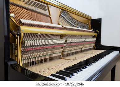 Internal parts of a black upright piano - keyboard, mechanics and strings - Powered by Shutterstock