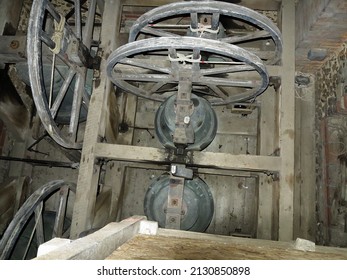 Internal view looking down from a belfry onto two cast iron bells and the wheel mechanism that works them 