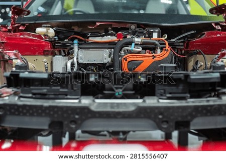 Internal view of modern EV powertrain and cooling system under the hood of a red car, real photo not AI.