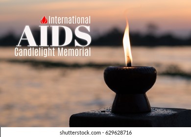 International AIDS Candlelight Memorial On May 18th With Candle Light Fire Lamp Nearby Abstract Background Silhouette River During Sunset Or Sunrise In Countryside. Candlestick In Evening Twilight.