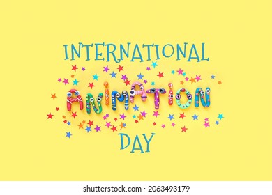 International Animation Day Concept. Funny Colorful Letters Of Plasticine On Yellow Background. Animation Professional Holiday. Flat Lay