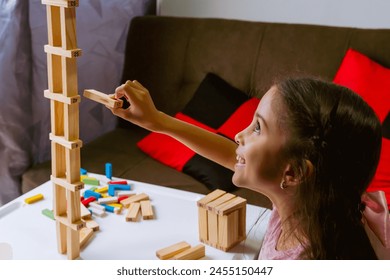 International Children Day. Pretty latin girl playing with colored blocks on a white table. Playful, creative and thinking games. Family day, happy children.