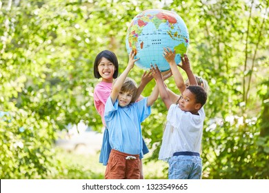 International Children Group As A Team Holds A Globe In Nature