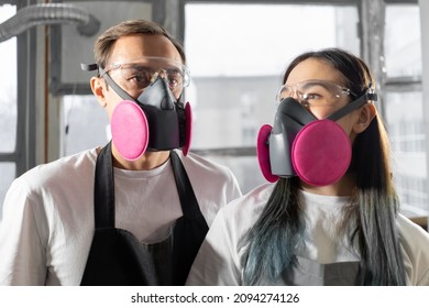 International Couple Man And Woman In Pink Respirators In A Workshop. Respiratory Protection.