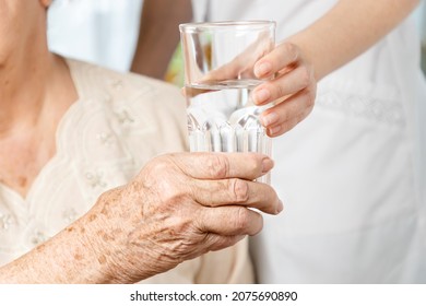 International Day Of Older Persons. A Nurse Gives A Glass Of Water To An Elderly Woman. Close Up Of Hands. Care For The Elderly In Nursing Homes.