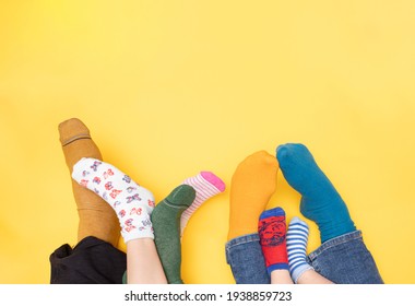 Día Internacional de personas con síndrome de Down, 21 de marzo. Pies de un niño pequeño con síndrome de Down, su hermana, madre y padre con un fondo amarillo con diferentes colores calcetines. Concepto de laya plana.