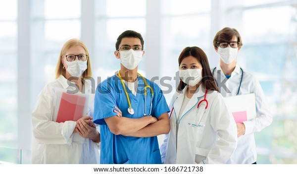 International doctor\
team. Hospital medical staff. Mixed race Asian and Caucasian doctor\
and nurse meeting. Clinic personnel wearing face mask and\
stethoscope. Coronavirus\
outbreak.
