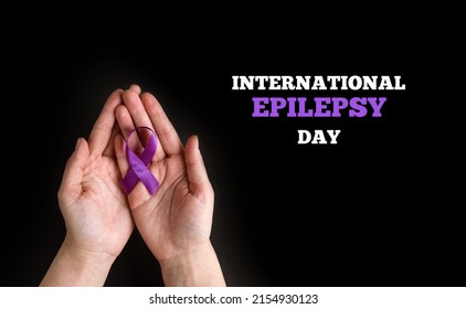 International Epilepsy Day. Woman Hands Holding Purple Ribbon On Black Background. Alzheimer's Disease, Pancreatic Cancer, Hodgkin's Lymphoma Awareness. World Lupus Day And World Cancer.