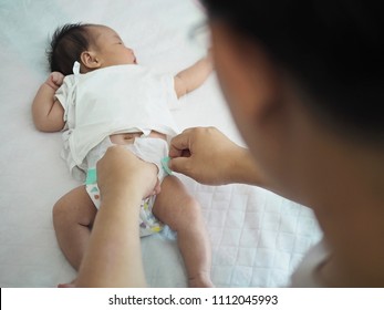 International Father Day concept hands of new daddy gently practice changing diaper for newborn baby on white bed.