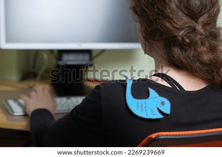 International Fool's Day. Woman at the workplace in the office with a fish glued on her back