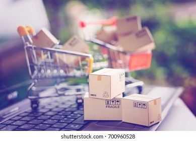 International freight or shipping service for online shopping or ecommerce concept : Paper boxes or cartons in a shopping cart on a computer notebook keyboard. Customer always buy things via internet.
