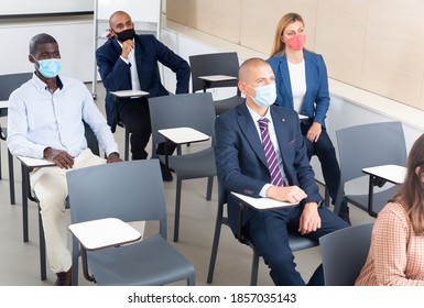 International Group Of Business People Wearing Protective Face Masks Listening To Presentation In Conference Room. Concept Of Precautions And Social Distancing In COVID 19 Pandemic..